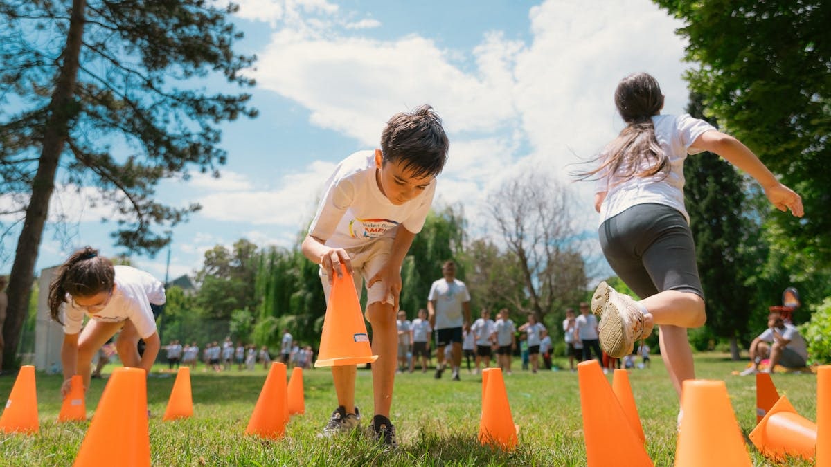 Children playing an obstacle course in a park on a sunny day, promoting fun and physical fitness.